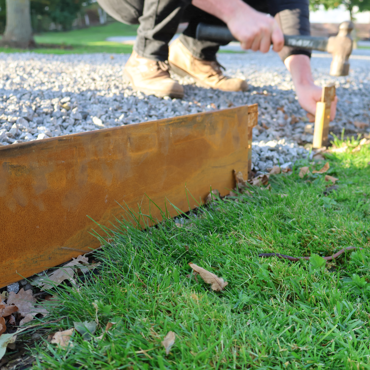 Groundline - Edge height 150mm GEO Steel garden edging being installed to create boundary between soil, planting and gravel path. Lawn edge, garden border, flower beds, raised edging. Metal, weathering steel, mild steel or powder coated steel.  Garden walkway, path and paving edging.