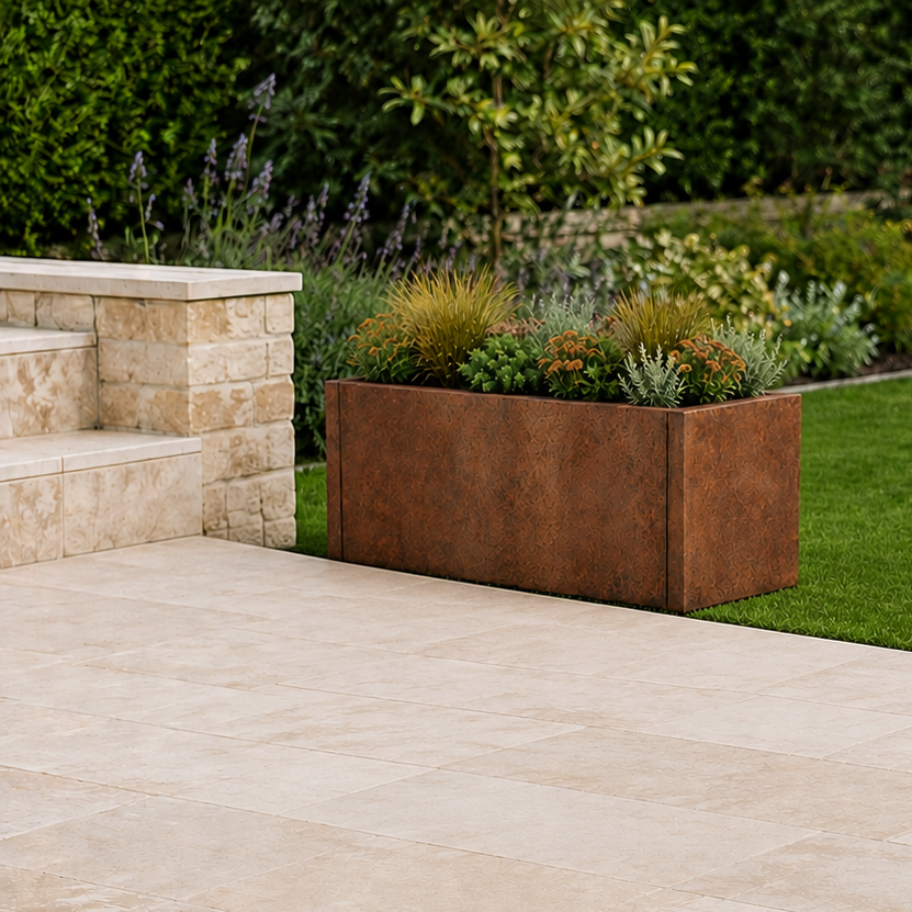 Beige stone pavers laid out in a modern outdoor patio area next to a green lawn and a rusted metal planter box. Corten steel planter tub